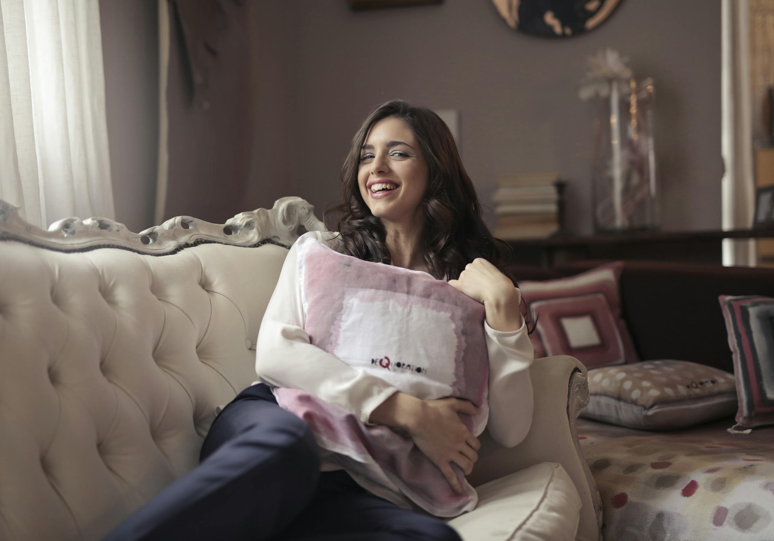 Woman enjoying a relaxed moment on a stylish sofa, exuding warmth and happiness in a cozy living room.